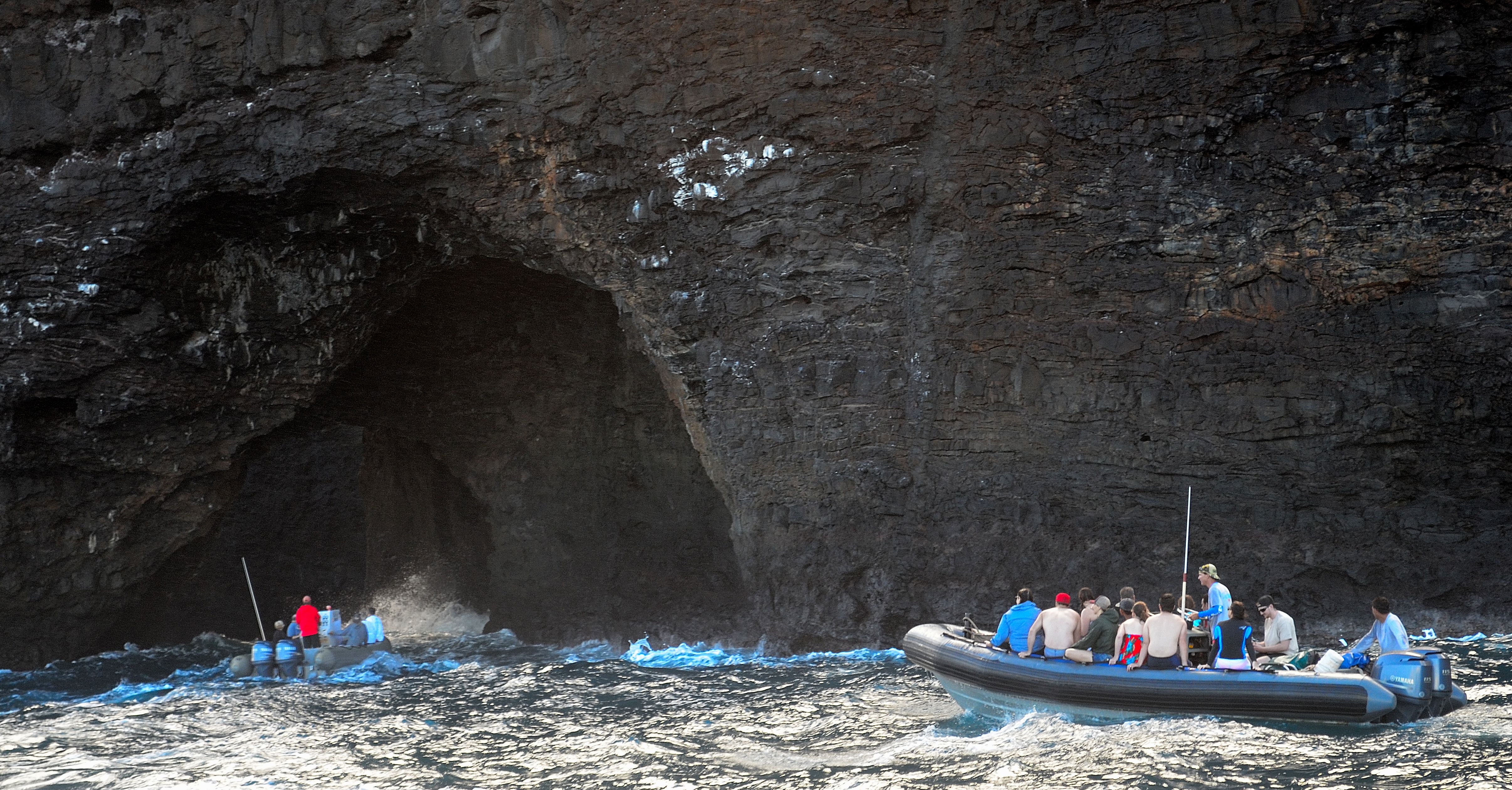 Two Zodiac rafts approaching a Na Pali sea cave